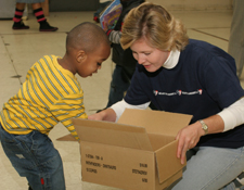 Angie gives a book to a child.